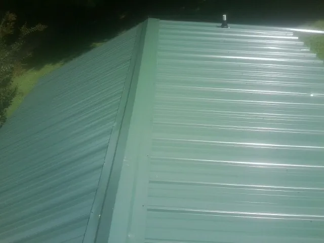 New green metal panels meeting at the ridge of a roof — Flat Roof Repair work by our crew in Alvarado