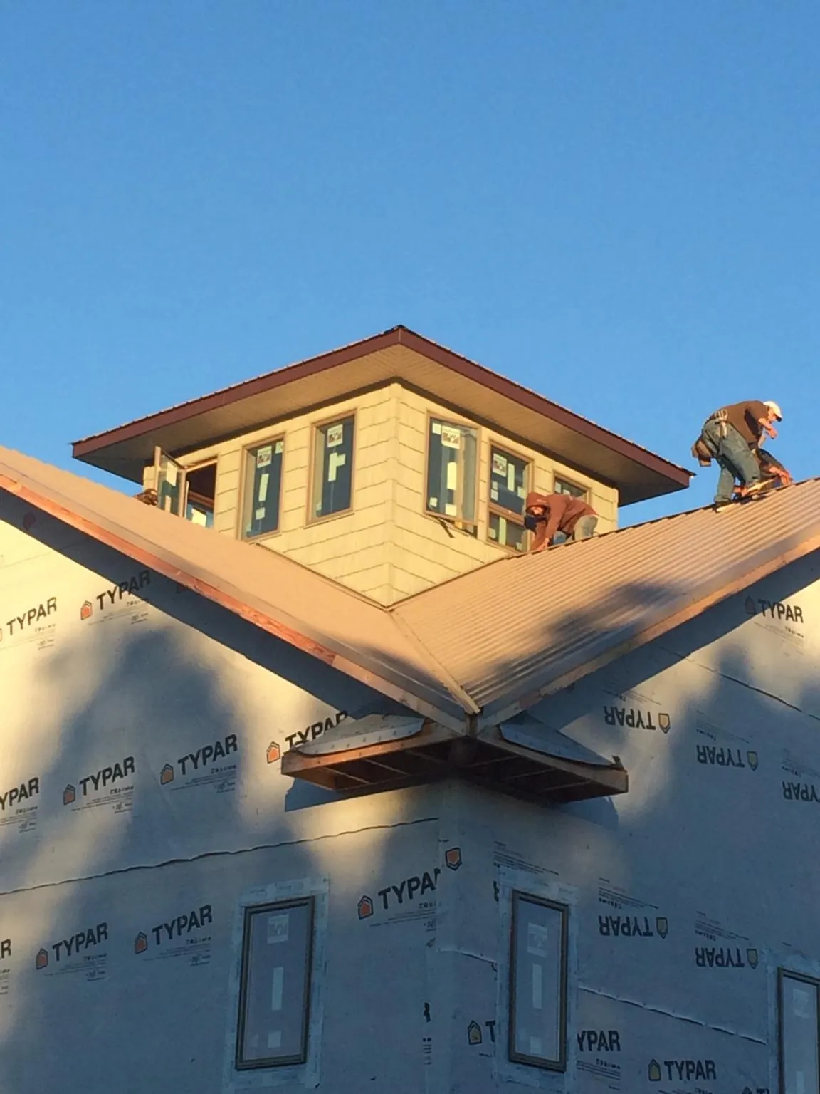 Roofers working around a rooftop cupola on a new metal roof at sunset — Roof Waterproofing in Alvarado by Roofing Brothers